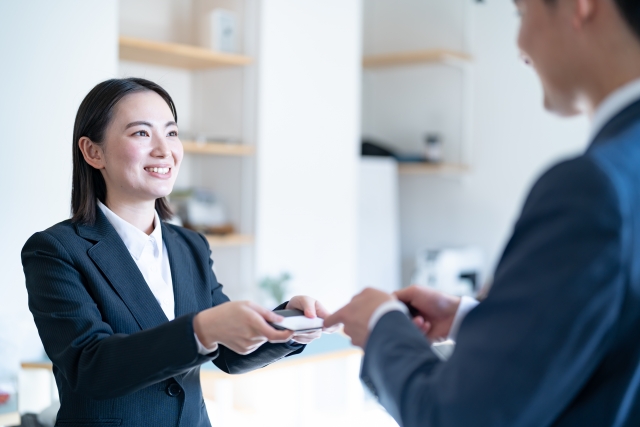 顧客と名刺交換する新卒女性