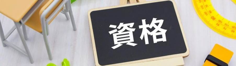 机上に並ぶ文房具と資格の文字が書かれた黒板のイメージ