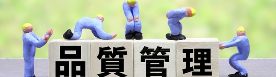 「品質管理」と書かれたブロックの上で作業している小さな作業員のフィギュアたちの写真