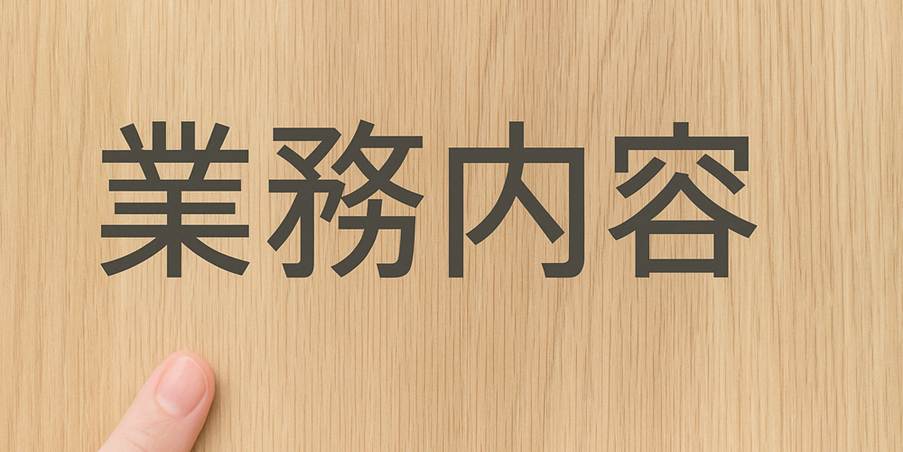 業務内容の文字と指が写った木目背景の画像