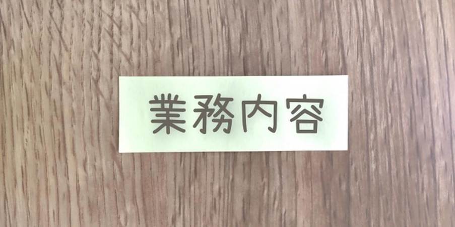 木目の背景に貼られた「業務内容」のラベル